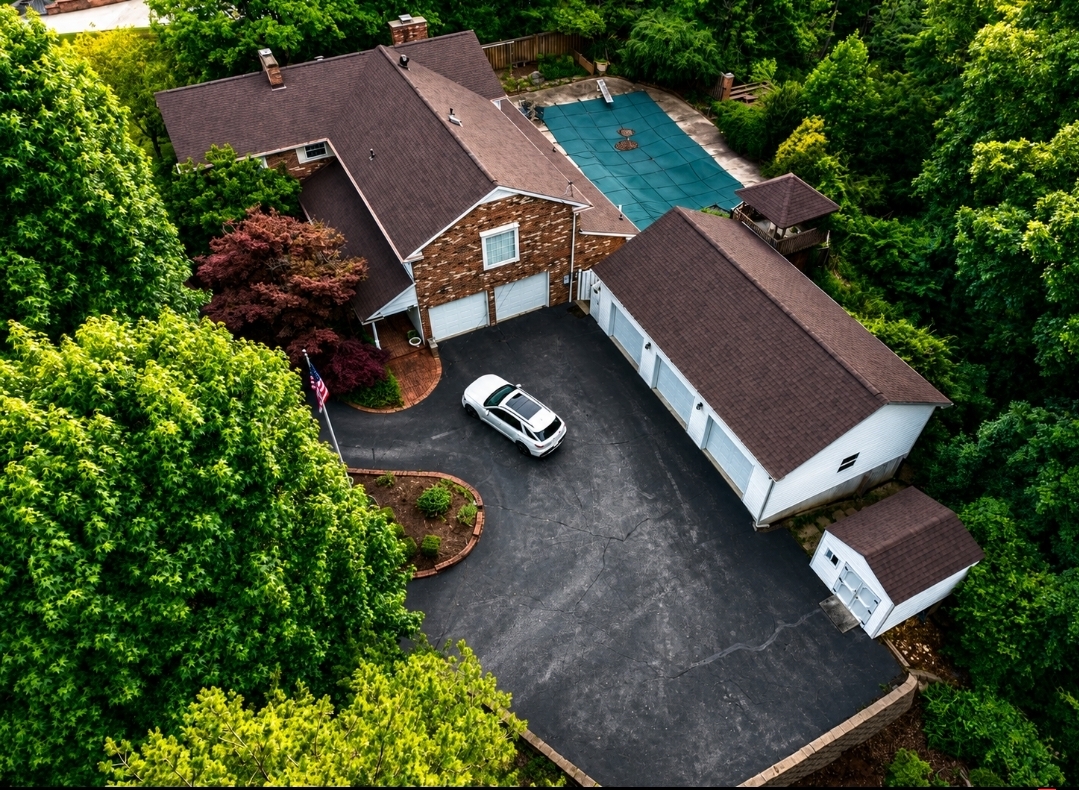 Aerial view of a brick home and detached garage with new shingle roofing