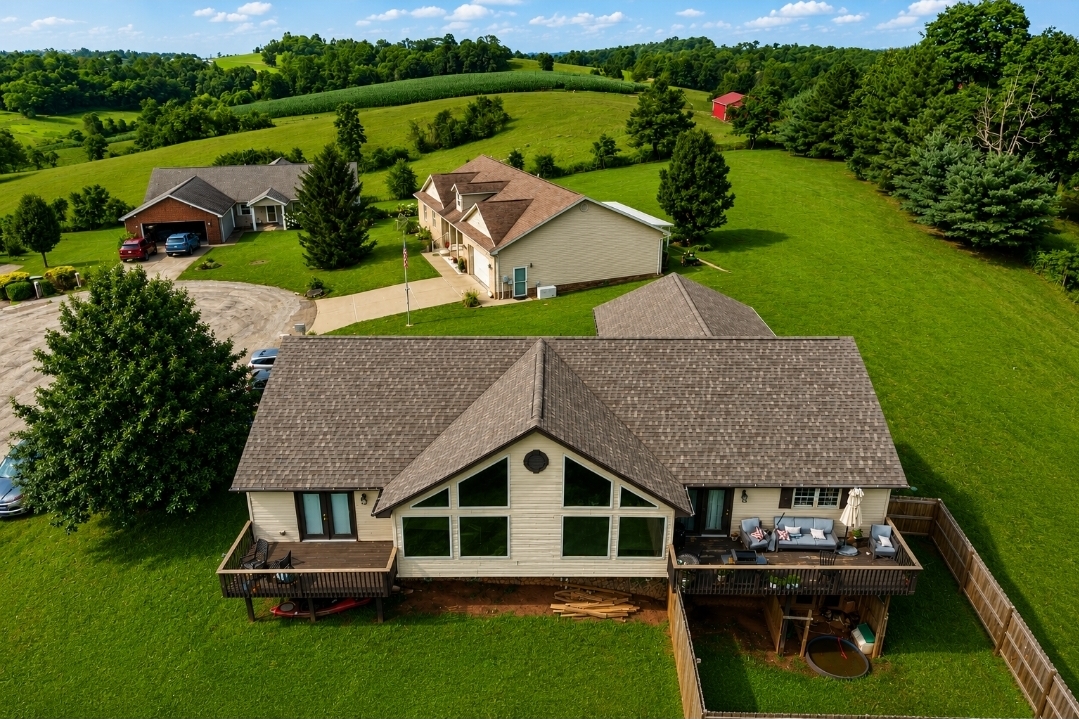 Country home with a freshly installed shingle roof surrounded by rolling hills